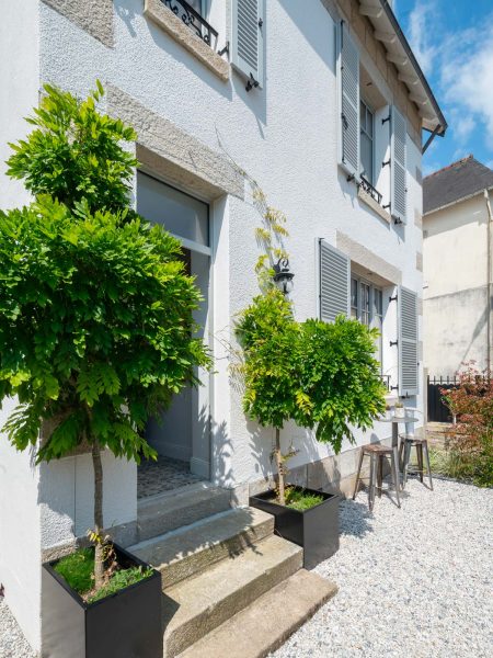 entrée de maison avec deux glycines qui montent en arche